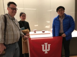 Posing with an "IU Red" bowl in the ceramics portion of the "Tsinghua Treasures: Exhibition of Tsinghua University Art Museum Collection." December 8, 2017. (L-R) Jason Jackson, Ge Xiuzhi, and Peter Wen. Photograph by Carrie Hertz.