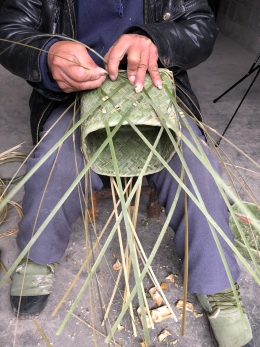 During his second day of work on it, Mr. Li Guicai added the functional and decorative base to the double-woven sticky rice basket with lid. December 15, 2017. Photograph by Jason Baird Jackson.