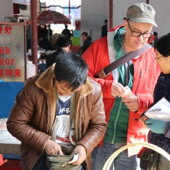 Zhang Lijun (R) and I (C) plan our purchase of baskets from Li Guozhong (L) at his stand on market day in Lihu town. December 16, 2017. Photograph by Jon Kay.