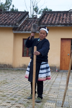 A Baiku Yao woman uses a mallet to drive posts used in preparing a loom for weaving. December 17, 2017. Photograph by Carrie Hertz.